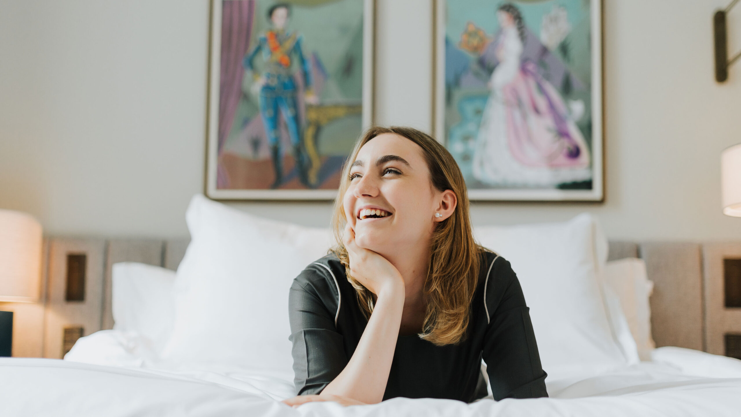 junge auszubildende im hotelfach liegt lachen auf gemachtem bett